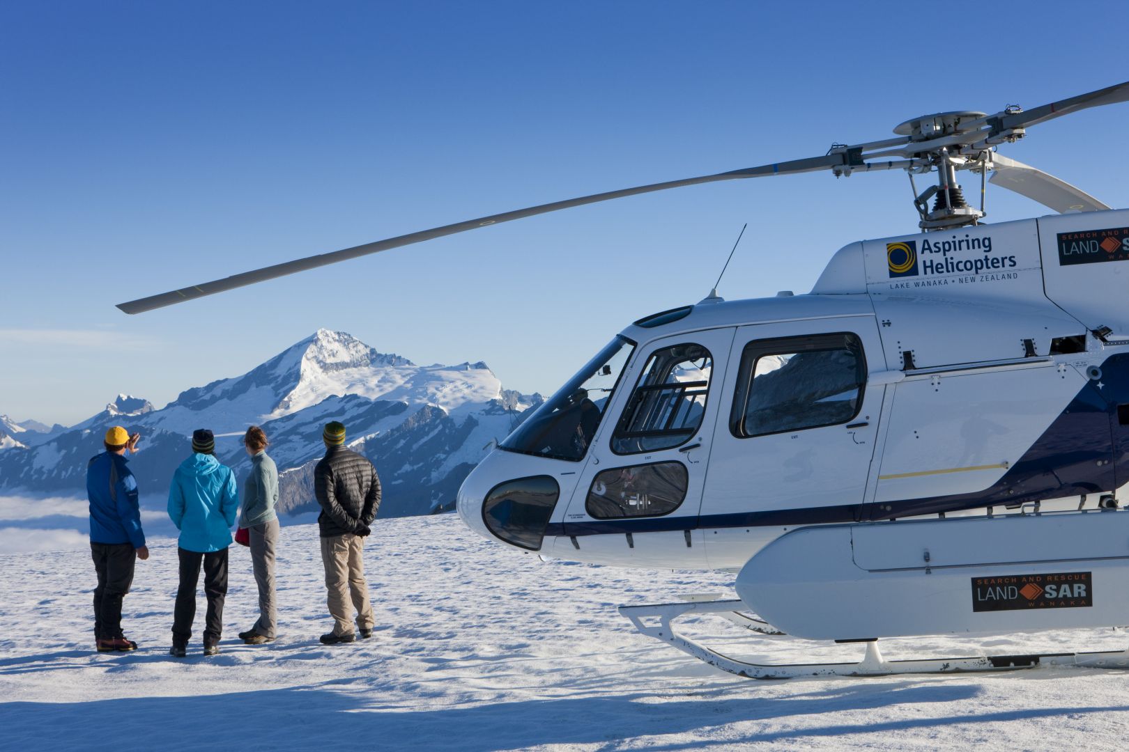 Four people enjoying a glacier landing admiring distant mountains in Wanaka.