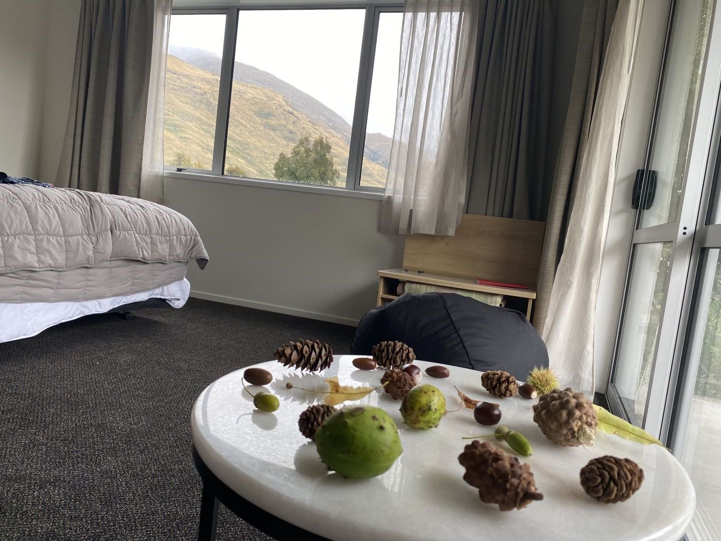 Interior of room at Wanaka Top 10 Holiday Park displaying pinecones and acorns on table collected by kids..