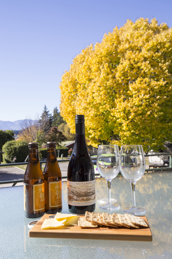 Local wine enjoying the view of the beautiful Golden Ash Tree while staying at Wanaka Top 10 Holiday Park.